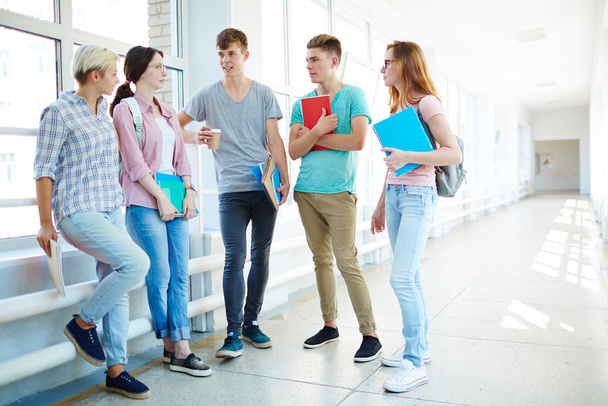 Teini-ikäiset keskustelevat koulutyöstä tauon aikana
 - Valokuva, kuva