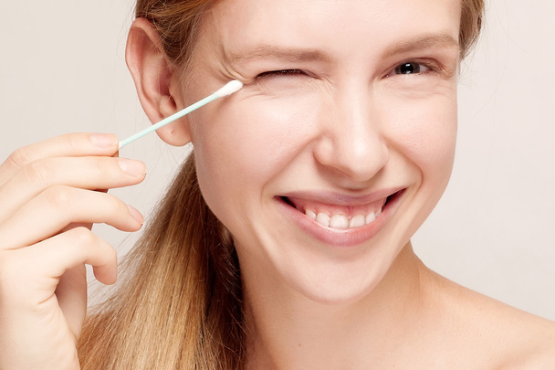 Happy beautiful young woman cleaning skin by cotton swab. - Foto, imagen