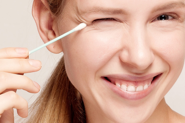 Happy beautiful young woman cleaning skin by cotton swab. - Photo, image