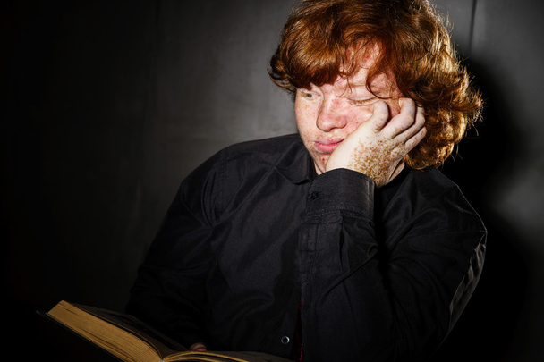 Freckled red-haired teenage boy reading book, education concept - Photo, image
