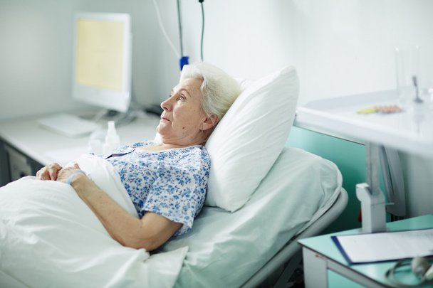 Senior patient lying in clinic bed  - Valokuva, kuva