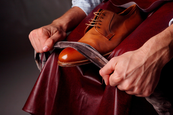 Мастер обуви чистит коричневые ботинки. Взгляд
 - Фото, изображение