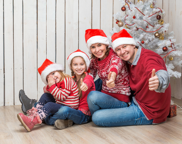family in Santa hats near the Christmas tree  - Foto, Imagen