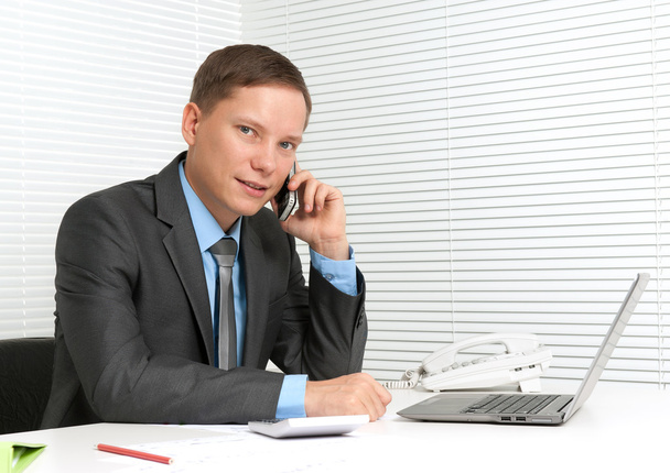 cheerful young business man using mobile phone at desk - Foto, Bild