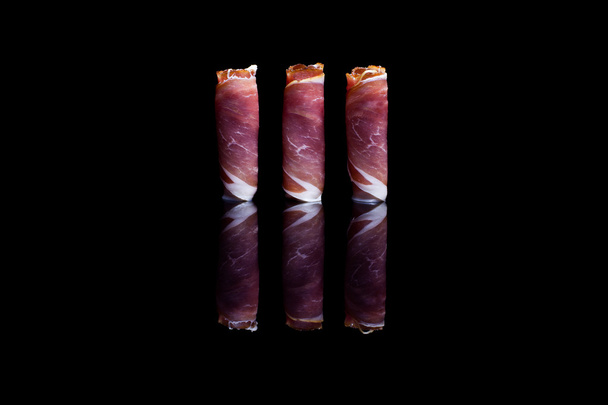 Three rolls of prosciutto ham positioned vertically - Photo, image