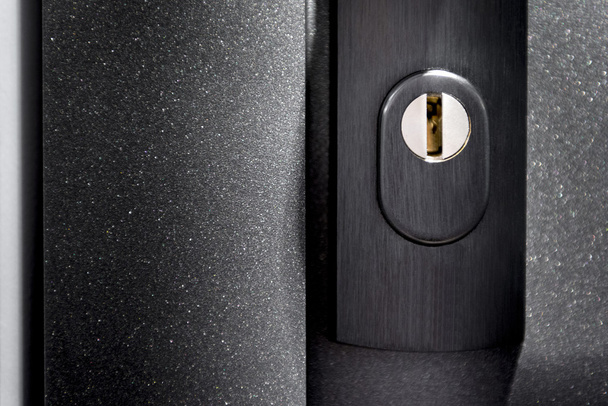 Dettaglio del foro della serratura in porta metallica nera
 - Foto, immagini