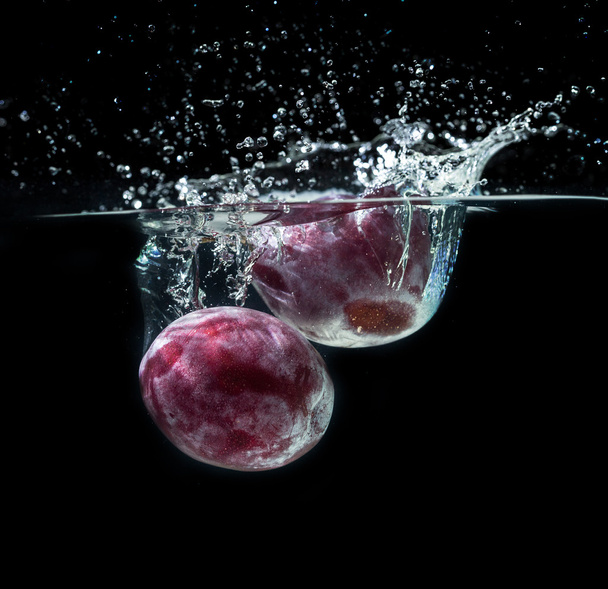 Fresh plums in water splash - Foto, afbeelding