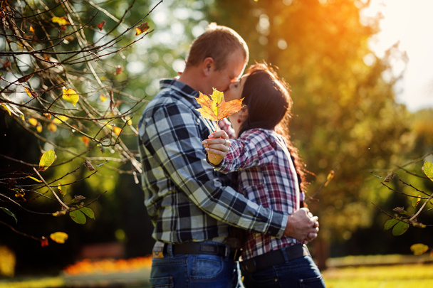 Cute couple outdoors in fall. Young man and woman kissing  hi - Фото, изображение