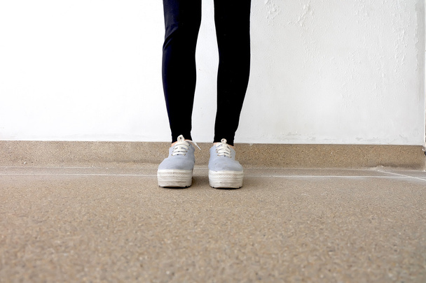 Young Fashion Woman's Legs in Jeans and Sneakers on Floor  - Foto, Bild