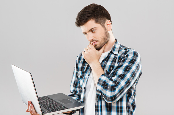 Thoughtful man looking at laptop - Фото, изображение