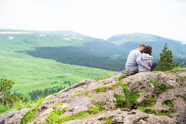 Amar jovem casal hipster sentado em uma montanha, abraçando e l
 - Foto, Imagem