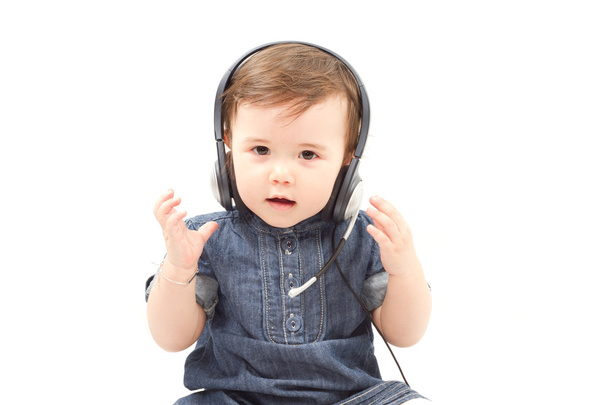 Portrait of baby little girl in earphones isolated on white background - 写真・画像