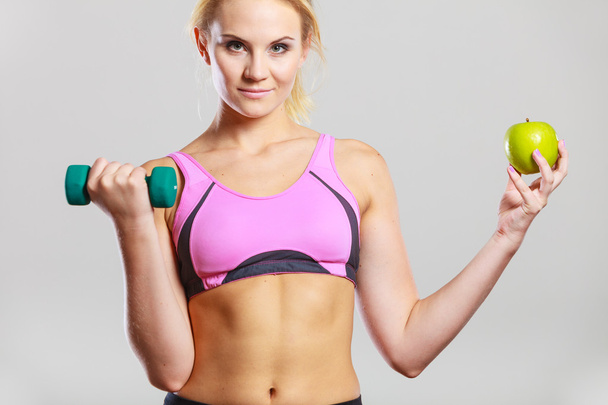 Diet fit body. Girl holds dumbbells and apple fruit - Fotó, kép
