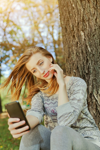 Meisje zit in het park en maakt selfie - Foto, afbeelding
