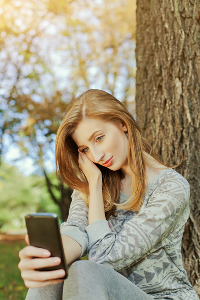 Chica sentada en el parque y hace selfie
 - Foto, Imagen