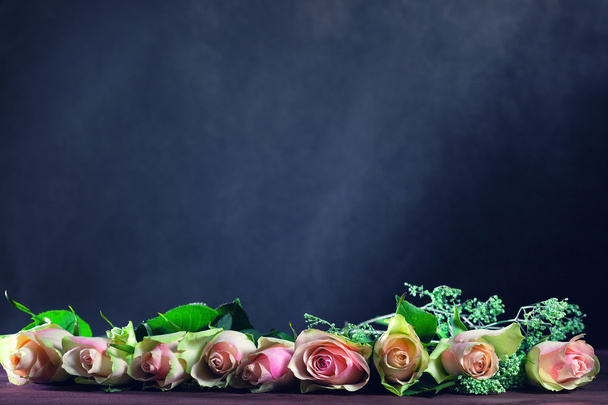 Flores de rosas están sobre la mesa sobre un fondo oscuro abstracto. Espacio para texto o imagen
 - Foto, imagen
