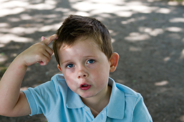 Little boy scratching his head - Фото, изображение