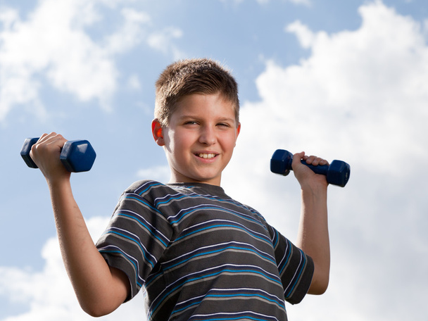 Boy lifting dumbbells outdoors - Foto, Imagen