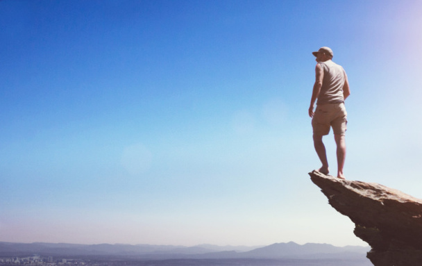 Muž na vrcholu mountian zobrazení dolů do údolí na obzoru - Fotografie, Obrázek