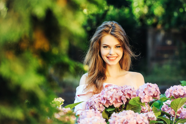 pretty smiling girl in hydrangea flowers - Foto, Imagem