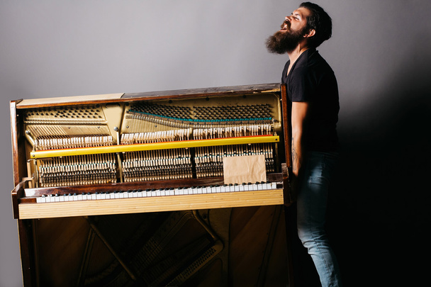 bearded man trying to move wooden piano - Φωτογραφία, εικόνα