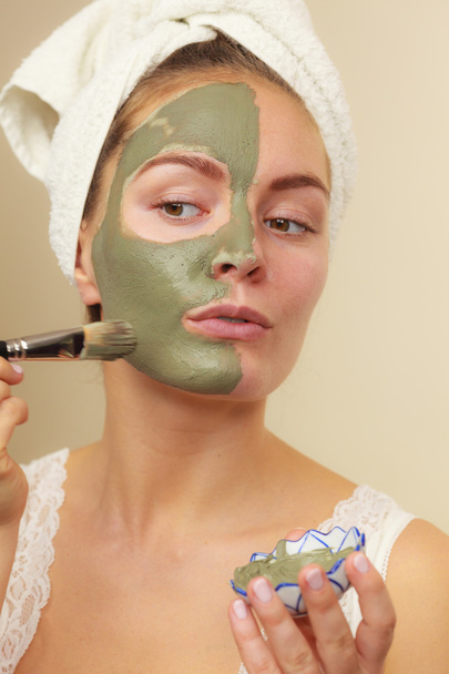 Woman applying with brush clay mud mask to her face  - 写真・画像