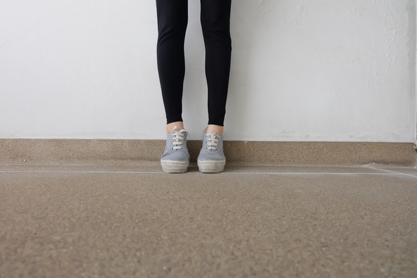 Young Fashion Woman's Legs in Jeans and Sneakers on Floor  - Photo, image