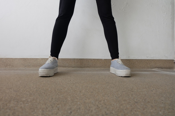 Young Fashion Woman's Legs in Jeans and Sneakers on Floor  - Foto, afbeelding