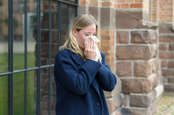Άρρωστη νεαρή γυναίκα φυσάει τη μύτη της - Φωτογραφία, εικόνα