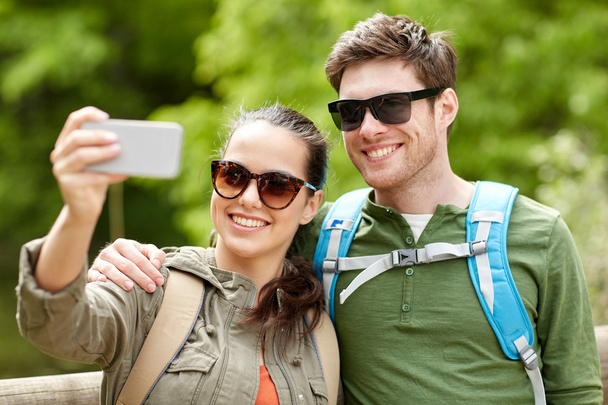couple with backpacks taking selfie by smartphone - Φωτογραφία, εικόνα