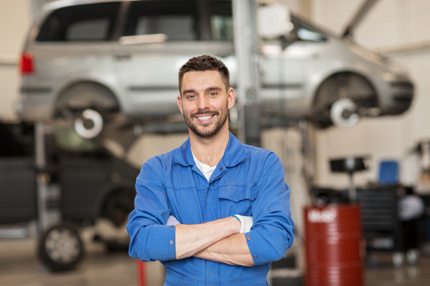 happy auto mechanic man or smith at car workshop - Foto, imagen