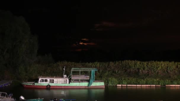 Nacht uitzicht op een haven met de oude boot en een maan stijgt op de achtergrond. Time-lapse 1080p - Video