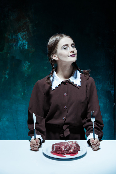 Bloody Halloween theme: crazy girl with a knife, fork and meat - Photo, image