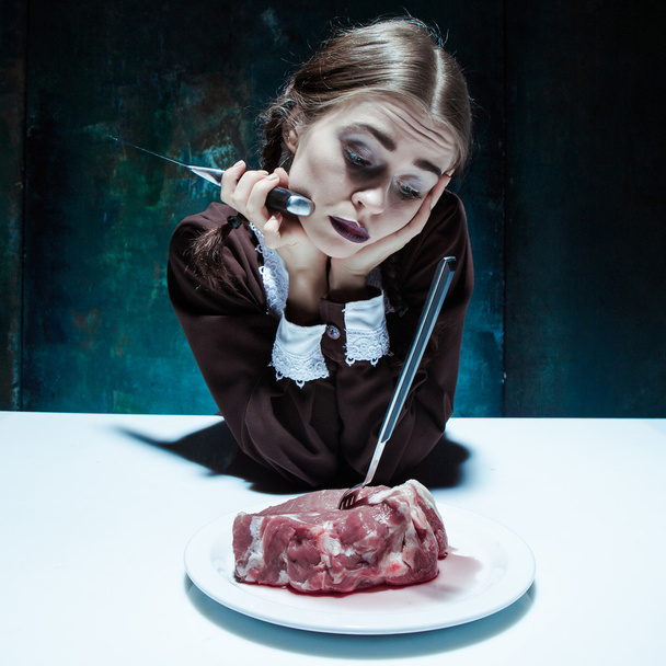 Bloody Halloween theme: crazy girl with a knife, fork and meat - Φωτογραφία, εικόνα