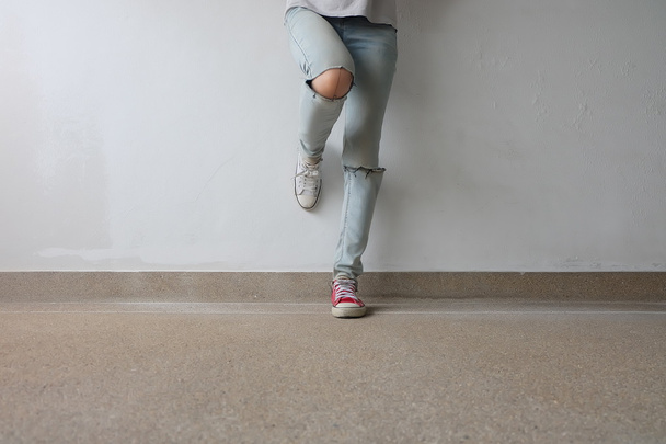 Young Fashion Woman's Legs in Blue Jeans and White, Red Sneakers on Floor  - Фото, изображение