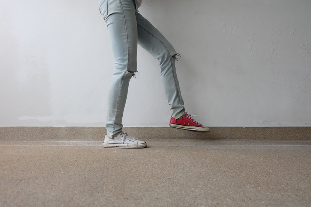 Piernas de mujer de moda joven en pantalones vaqueros azules y blancos, zapatillas rojas en el piso
  - Foto, imagen