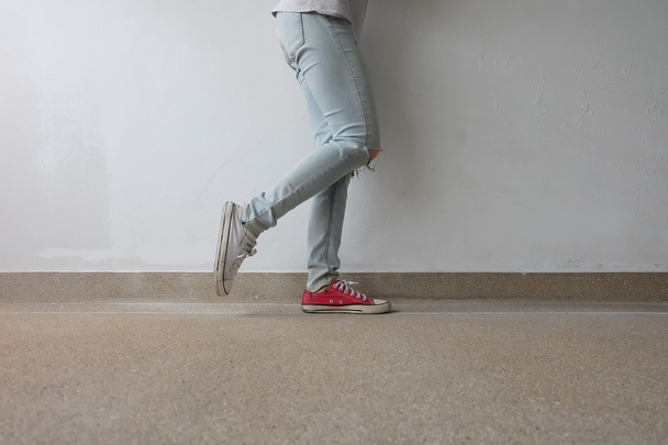 Young Fashion Woman's Legs in Blue Jeans and White, Red Sneakers on Floor  - Foto, Bild