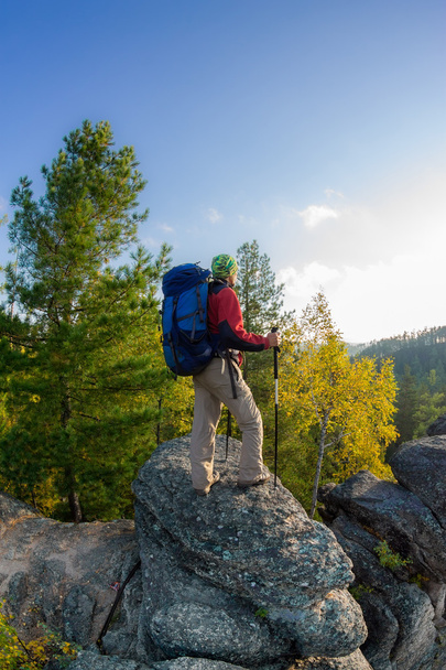 Man with backpack and trekking pole in bandana standing on a roc - Foto, Bild