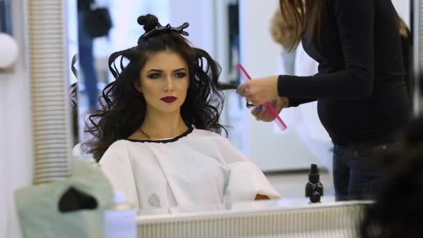 Peluquero hace vestido de pelo hermosa chica en un salón de belleza
 - Metraje, vídeo