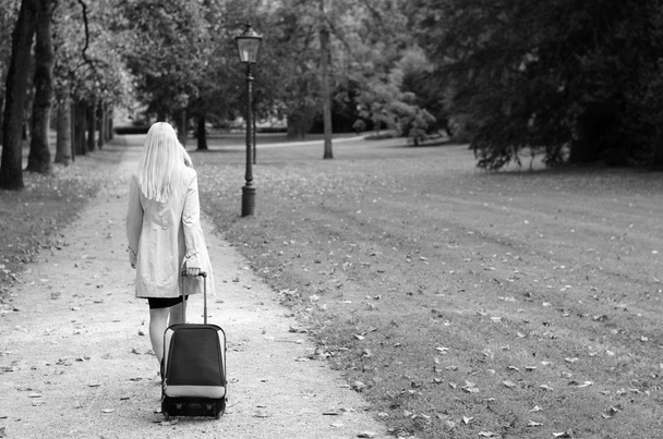 женщина тащит чемодан в черном и белом
 - Фото, изображение