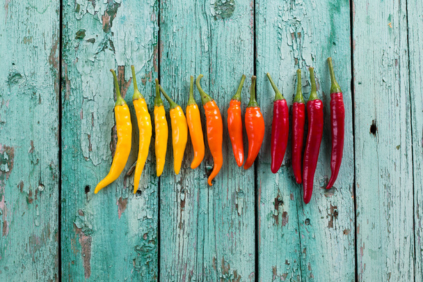 many vibrant colors on peppers , old wooden background - Foto, imagen