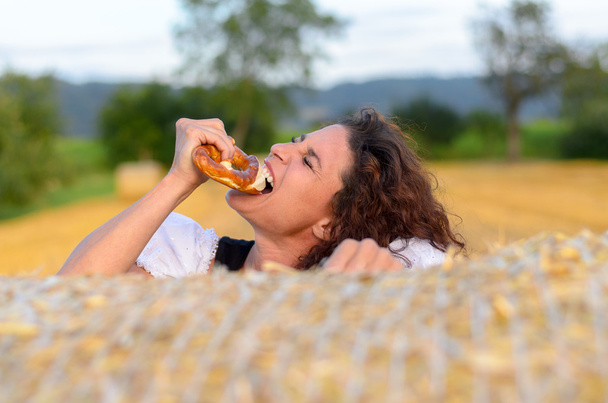 Mujer joven mordiendo un pretzel quebradizo
 - Foto, Imagen