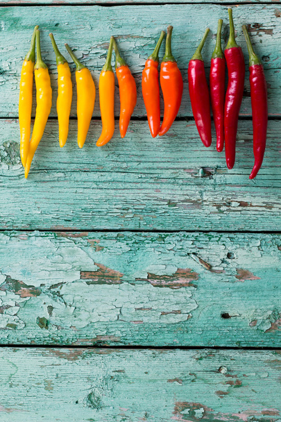 many vibrant colors on peppers , old wooden background - Фото, зображення