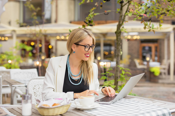 Femme d'affaires assise dans un café extérieur et travaillant sur un ordinateur portable
 - Photo, image