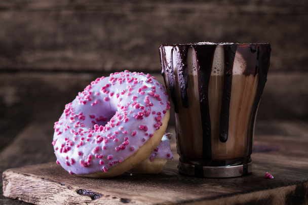 donuts and a cup of coffee with chocolate on a wooden table - Zdjęcie, obraz