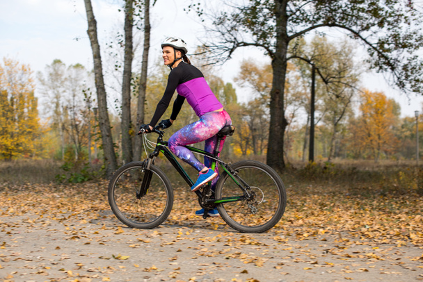 Woman cycling in autumn park - Zdjęcie, obraz