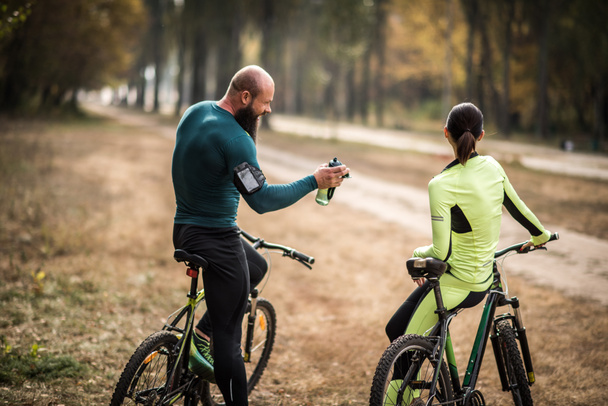 Couple of cyclists in autumn park - Foto, afbeelding