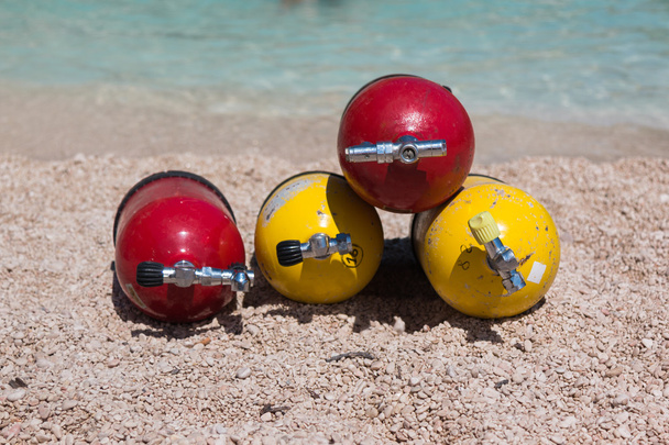 Tanques de oxigênio vermelho e amarelo para mergulhadores em uma praia
 - Foto, Imagem