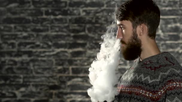 Молодой человек с бородой выкуривает электронную сигарету. Парящий испаритель хипстерского дыма в замедленной съемке
  - Кадры, видео