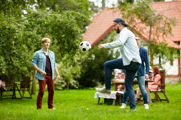 happy friends playing football at summer garden - Photo, image